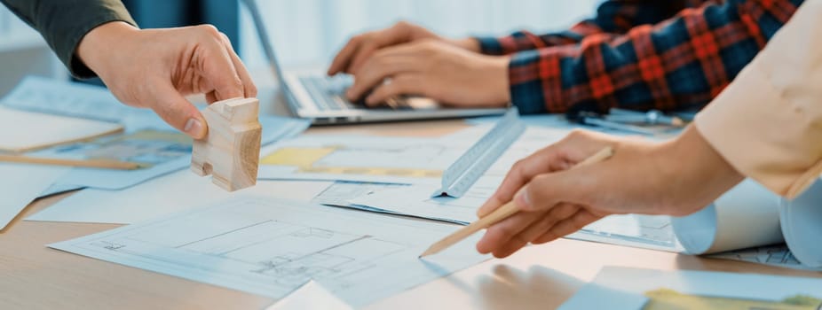 Skilled architect team using architectural equipment during colleague discussion about building design at meeting table with blueprint scatter around. Closeup. Focus on hand. Delineation.