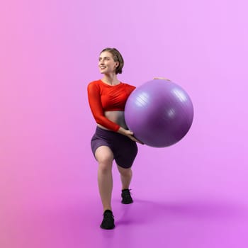 Full body length gaiety shot athletic and sporty young woman with fitness exercising ball in standing posture on isolated background. Healthy active and body care lifestyle.