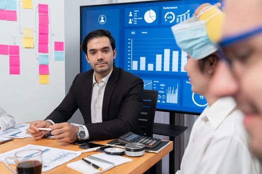 Diverse group of business analyst team analyzing financial data report. Finance data analysis chart and graph dashboard show on TV screen in meeting room for strategic marketing planning. Habiliment