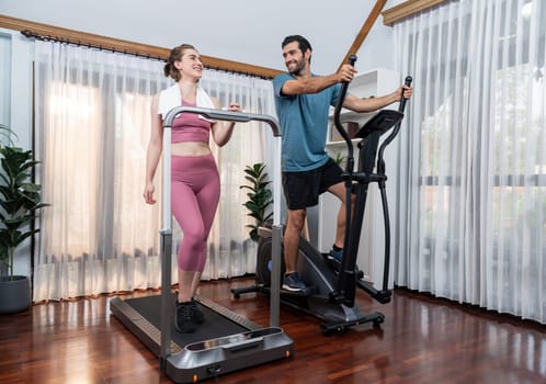 Athletic and sporty young couple or fitness buddy running on running machine together, home body workout exercise session as healthy sport lifestyle at home. Gaiety home exercise workout training.
