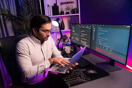 Smart IT developer working on laptop to type searching in software coding system at neon light office room, creating application program update latest version online website database online. Surmise.