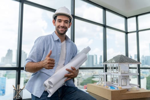 Portrait of professional architect engineer thinking about modern house project while wearing safety helmet and casual outfit. Smart interior designer holding project plans near house model. Tracery.