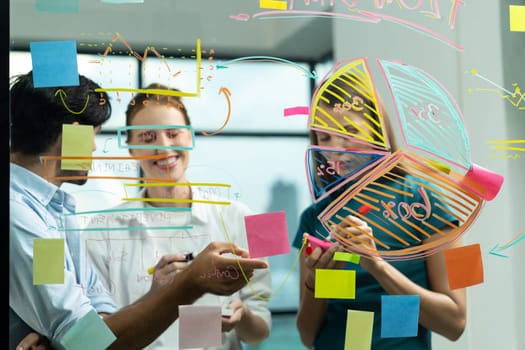 Smart business team working together, brainstorming idea at glass wall. Group of businesspeople corporate working, planing, thinking, sharing business plan while writing on glass wall. Tracery.