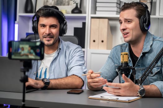 Host channel of creative broadcaster living by smartphone in positive podcast with special guest in list script to advice listeners, wearing headsets, using mic radio record at studio. Sellable.