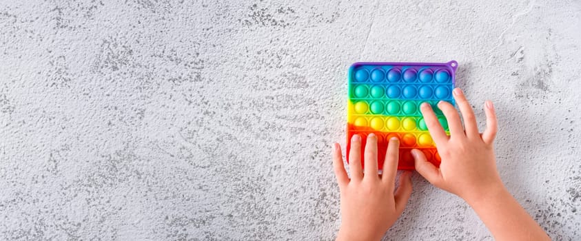 Top view of rainbow antistress sensory toy fidget push pop it on stone background