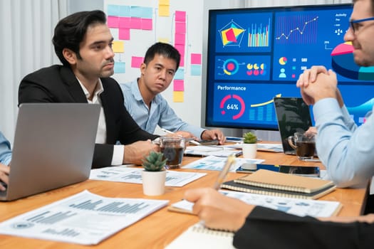 Diverse group of business analyst team analyzing financial data report. Finance data analysis chart and graph dashboard show on TV screen in meeting room for strategic marketing planning. Habiliment