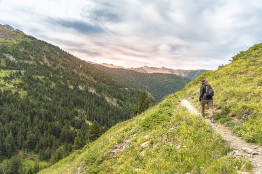 Young Woman With A Backpack Climbs To The Top Of The Mountain Against The Sunset. Discovery Travel Destination Concept. High quality photo