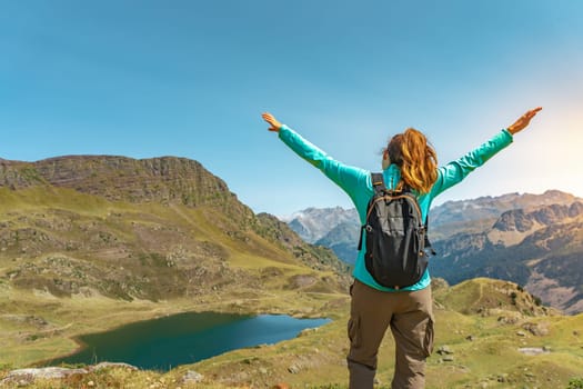 Attractive young woman with open arms enjoying life in the middle of a mountain with a lake in a beautiful landscape. High quality photo