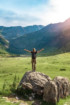 Female hiker in top of a rock with arms raised enjoying amazing landscape in summer. Vertical high quality photo.