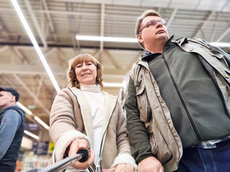 A middle-aged couple is shopping in brightly lit retail store, looking around with interest