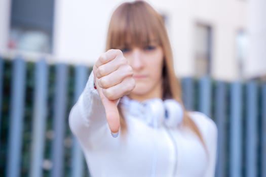 Close-up of pensive teenage female student pointing thumbs down.confident facial expression.