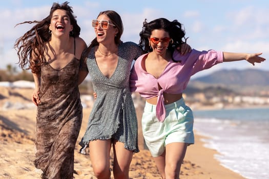 Cheerful multiethnic friends with sunglasses happy on vacation on the beach, looking at the camera.