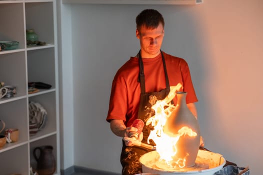 A potter burns a jug with a gas burner on a potter's wheel