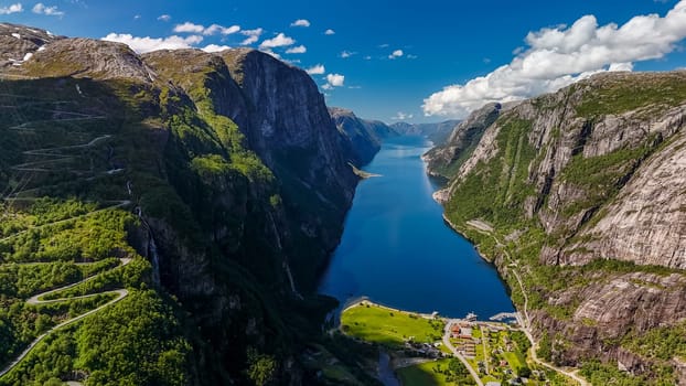 Lysebotn, Lysefjorden, Norway A winding road cuts through lush green mountainsides overlooking a serene fjord in Norway.