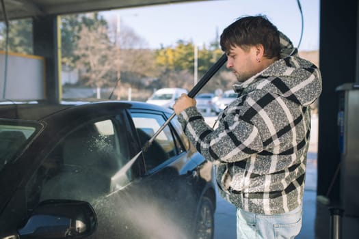 Cleaning car using active foam. Man washing his car on self car-washing