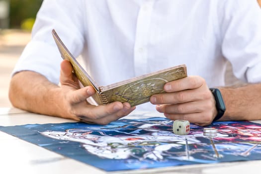 Background of Playing Field , Man Holding Book of Game, Studying Rules Instructions for Leela, Hands Close-Up, Turkey, Alanya - April 14, 2024