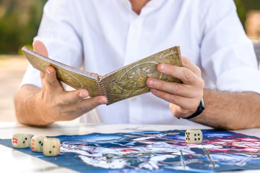 Instructions for Game of Leela: Man Holds Book in Hands, Close-Up Against Playing Field Background, Studying Rules, Turkey, Alanya - April 14, 2024