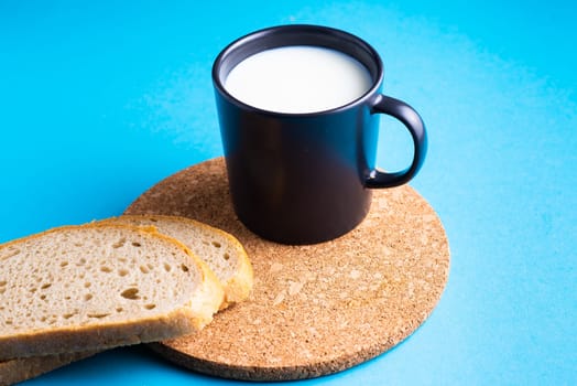 Breakfast bread and cup of milk on yellow and blue background