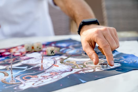 Ancient Indian Game Leela: Close-Up of Hands on Background with Game Board, Man Moves Game Chip in Form of Ring After Rolling Dice, Turkey, Alanya - April 14, 2024