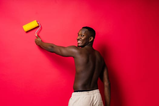 Happy construction worker holding paint roller performing interior renovation with an optimism.