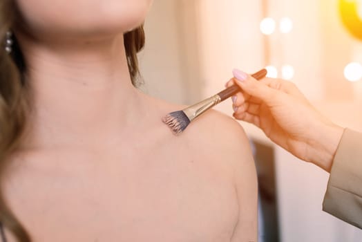 Makeup artist applies lipstick. Hand of make-up master, painting lips of a young beauty model.