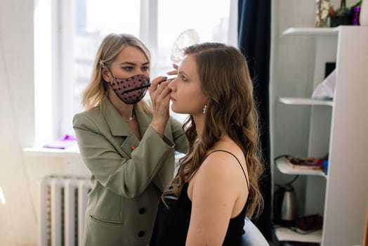 Makeup artist applies lipstick. Hand of make-up master, painting lips of a young beauty model.
