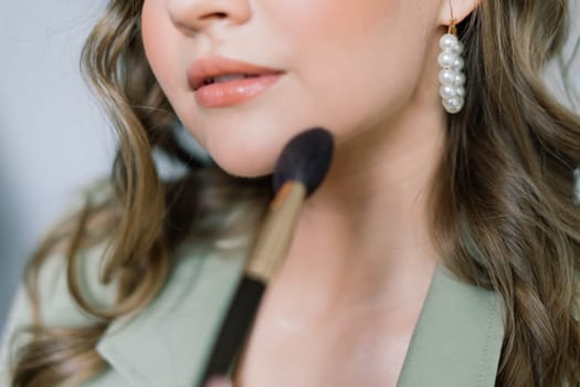 Makeup artist applies lipstick. Hand of make-up master, painting lips of a young beauty model.