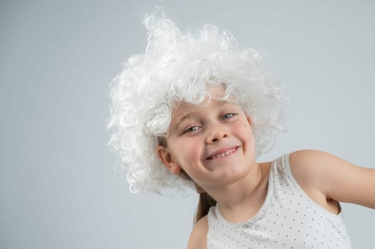 Portrait of a little Caucasian girl wearing a white curly wig on a white background