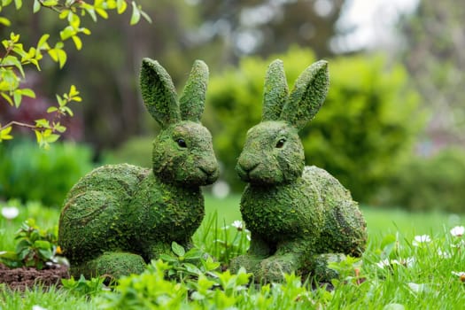 Two rabbits sitting on green grassy field in front of tree with nature beauty and peaceful atmosphere