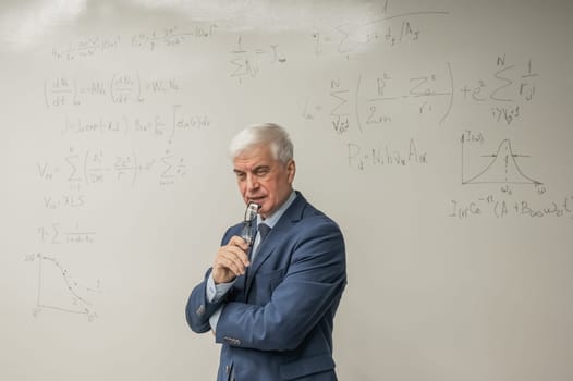 Mature man stands at a white board with written formulas