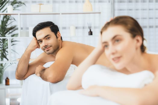 Blissful couple customer having exfoliation treatment in luxury spa salon with warmth candle light ambient. Salt scrub beauty treatment in health spa body scrub. Quiescent