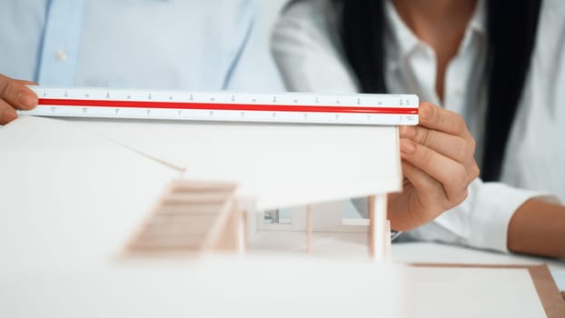 Professional engineer measures house model while skilled designer writes down in blueprint. Work together, collaboration, cooperate. Creative design and team working concept. Closeup. Immaculate
