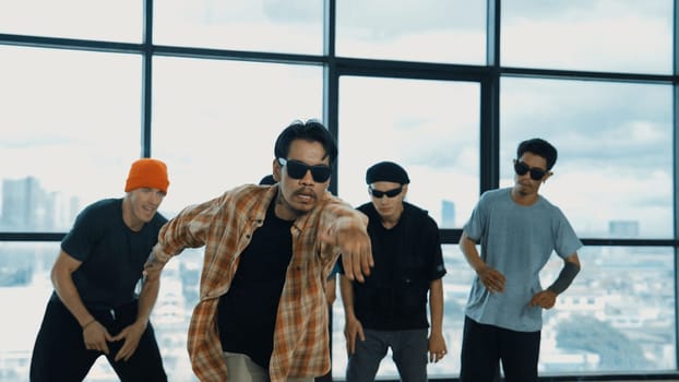 Multicultural hipster group looking at camera while perform break dancing at building with sky scrapper or city view. Street dancer team looking at dancer performance. Outdoor sport 2024. Endeavor.