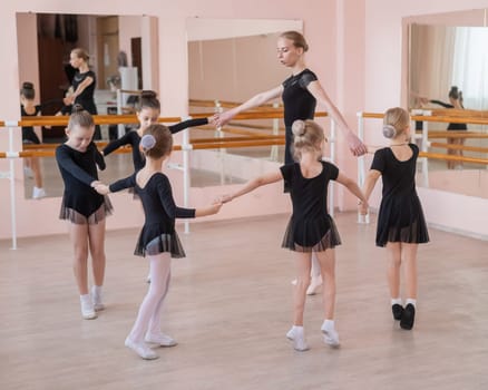 Children's ballet school. Caucasian woman teaching ballet to little girls