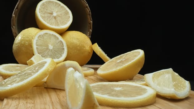 Close up of lemon slices are meticulously arranged against a rustic basket backdrop on a deep black surface. Each slice, bathed in soft light against the dark background, Macrography. Comestible.