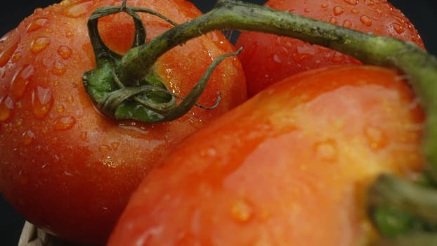 Macrography, tomatoes nestled within a rustic wooden basket are showcased against a dramatic black background. Each close-up shot captures the rich colors and textures of the tomatoes. Comestible.