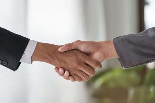 Two businessmen shaking hands and signing a contract, symbolizing a successful business deal in a modern office environment.