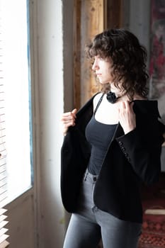 young beautiful woman posing in the studio, standing in black clothes near the window