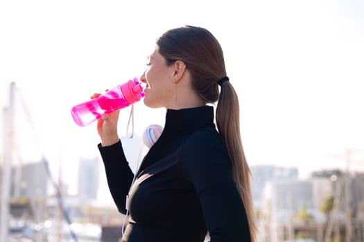 athletic woman smiling drinking water while exercising