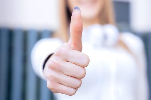 Close-up of happy teenage female student pointing thumb up. Facial expression of joy