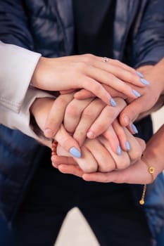 Happy young multiethnic students stacking hands in the city