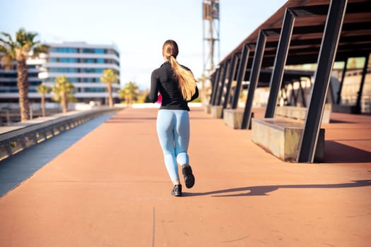 Fitness girl is running outdoors. Concept of workouts and healthy lifestyle.