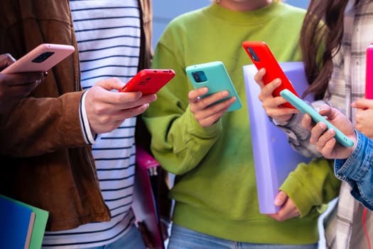 Group of friends using looking at their smartphones Multiracial teenagers browsing the internet with mobile phone on campus