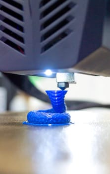 3D printer close up. A working 3D printer in process of printing object from molten plastic. 3D printer creating model by flowing liquid plastic from an extruder of printer. 3D printing technology