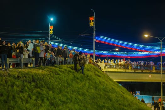 crowd of Russian people at road on the hill and bridge are watching fireworks in a night sky in Tula, Russia - May 9, 2021