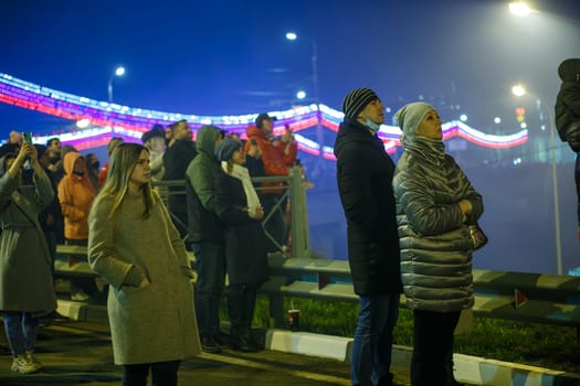 crowd of Russian people on the street are watching fireworks in a night sky in Tula, Russia - May 9, 2021