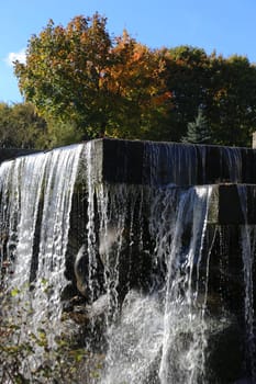 A fast flowing waterfall against the backdrop of autumn trees.