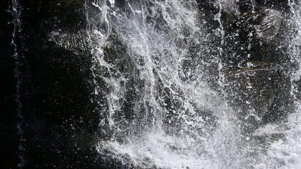 Dark Waterfall. Moving stream of water. The flow of water crashing against dark stones.