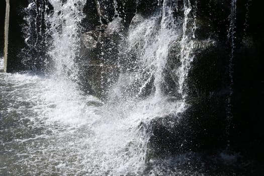 Splashing water from a creek. The flow of water crashing against dark stones.