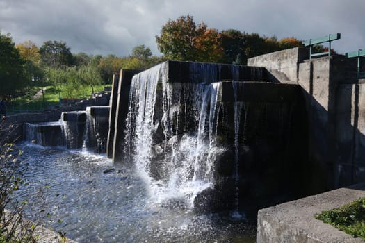 A fast flowing waterfall against the backdrop of a forest on the river bank.